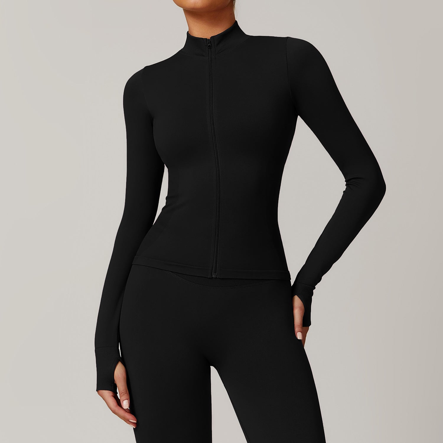 Black athletic jacket and leggings on a neutral background