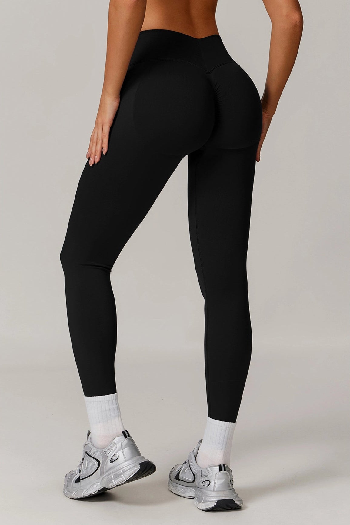 Person wearing black leggings and white sneakers on a plain background